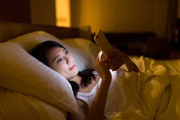 Mulher trabalhando no celular na cama à noite — Fotografia de Stock