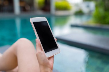 Cep telefonu kullanarak ve yüzme havuzunun yanısıra yatan kadın