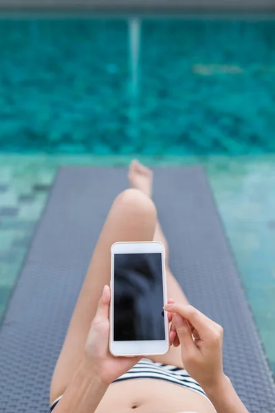 Vrouw met behulp van mobiele telefoon in zwembad — Stockfoto