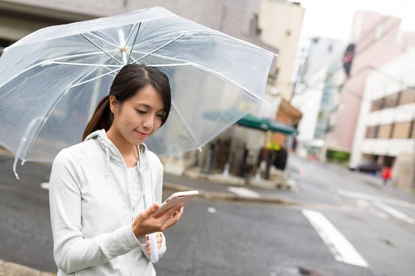 Woman holding umbrella and using mobile phone — Stock Photo, Image