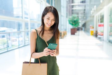 Alışveriş merkezinde cep telefonu kullanan kadın