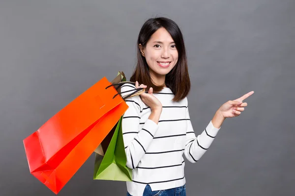 Mulher segurando sacos de compras e dedo apontando para cima — Fotografia de Stock