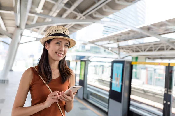 Mulher usando telefone celular na estação de trem — Fotografia de Stock