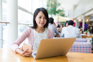 Dizüstü bilgisayarda çalışarak ve cep telefonu kullanan kadın