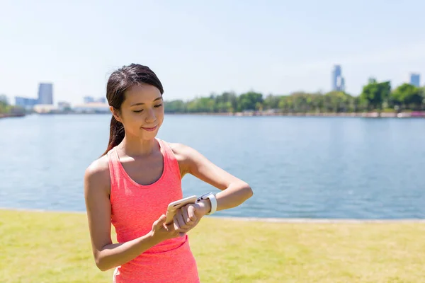 Woman using smart watch at green park