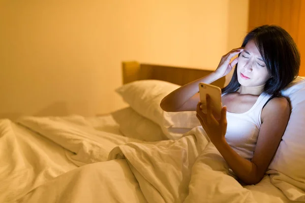 Женщина использует мобильный телефон и чувствует головную боль — стоковое фото