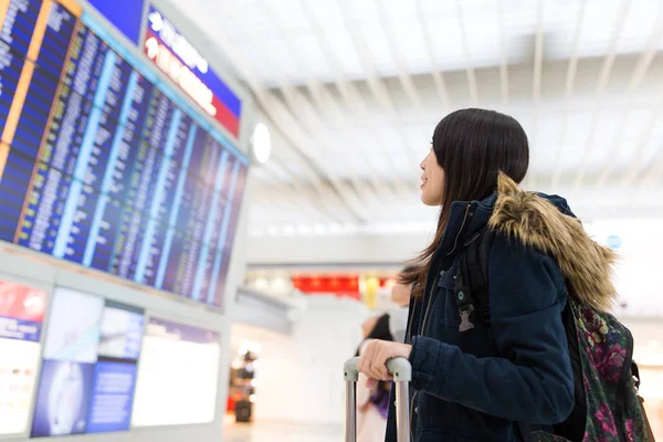 Vrouw kijken naar informatiebord en haar vlucht controleren — Stockfoto