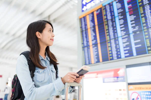 Vrouw kijken naar informatiebord in luchthaven — Stockfoto