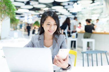 Dizüstü bilgisayar ve cep telefonu üzerinde çalışan iş kadını