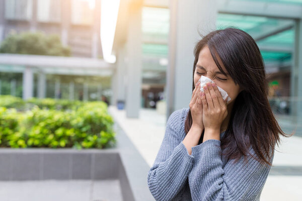 Woman sneezing at outdoor