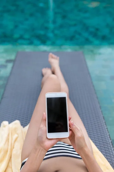 Vrouw met behulp van mobiele telefoon in zwembad — Stockfoto