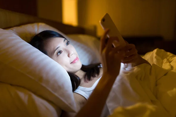 Femme utilisant un téléphone portable sur le lit la nuit — Photo