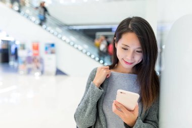 Alışveriş merkezinde cep telefonu kullanan kadın