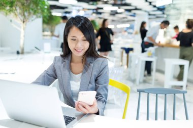 Cep telefonu ve dizüstü bilgisayar üzerinde çalışan iş kadını