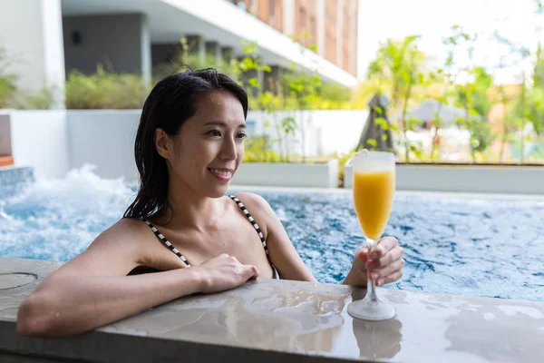 Женщина в джакузи бассейн и насладиться сочным напитком — стоковое фото