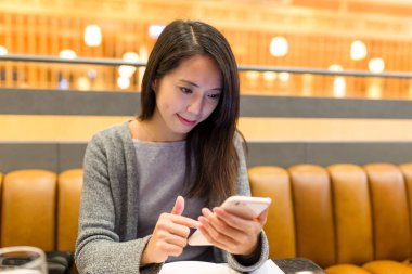 Restoranda cep telefonu kullanan kadın