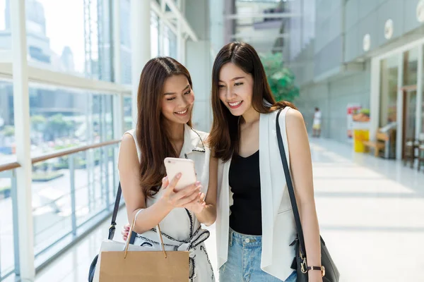 Las mujeres van de compras juntas y usan el teléfono celular — Foto de Stock