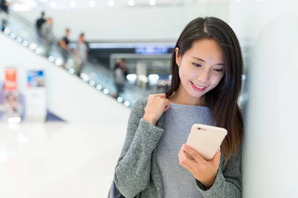 Vrouw met behulp van mobiele telefoon in winkelcentrum — Stockfoto
