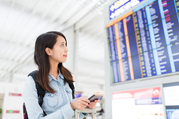 Vrouw kijken naar de weergave van de vlucht in luchthaven — Stockfoto