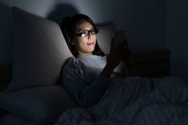 Жінка дивиться на мобільний телефон вночі — стокове фото