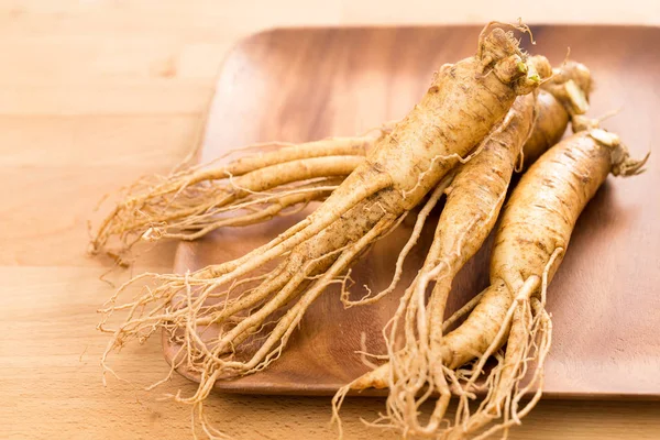 Tuore ginseng puulautasella — kuvapankkivalokuva