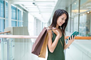 kağıt torba tutarak ve cep telefonuyla kadın