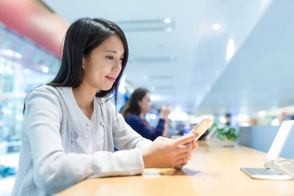 Vrouw met behulp van mobiele telefoon in restaurant — Stockfoto