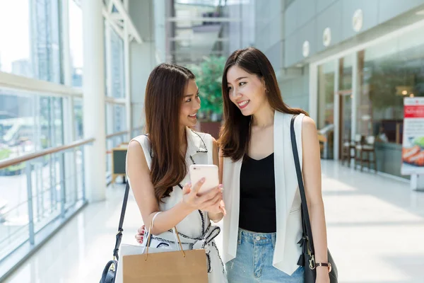 Meninas andando no centro comercial e usando o celular — Fotografia de Stock