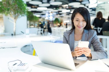 Cep telefonu ve dizüstü bilgisayar kullanarak iş kadını