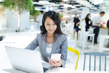 Cep telefonu ve dizüstü bilgisayar üzerinde çalışan iş kadını