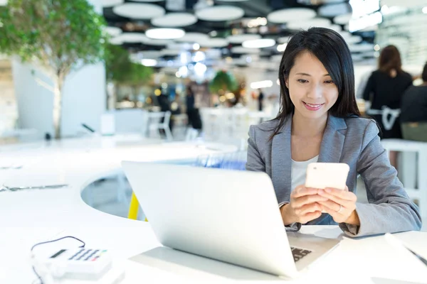 Cep telefonu ve dizüstü bilgisayar kullanarak iş kadını