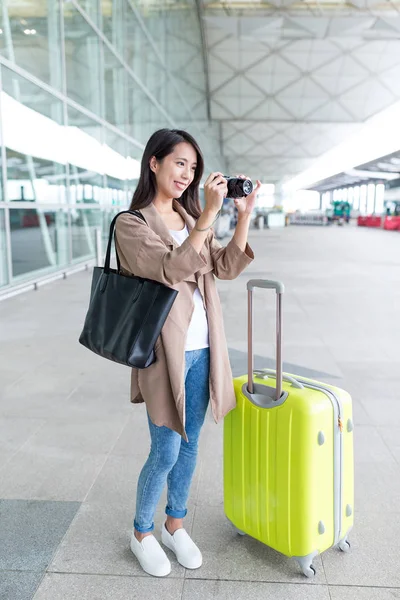 Woman taking photo with her luggage in airport — Stock Photo, Image