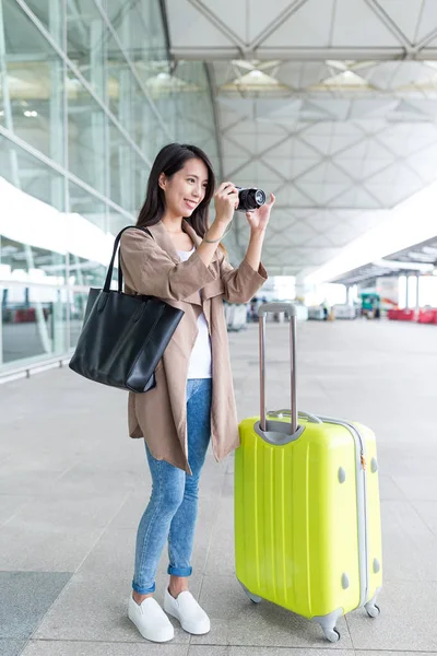 Mujer disparando por cámara con su equipaje en el aeropuerto — Foto de Stock