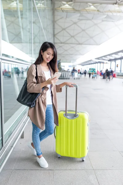 Woman checking email on cellphone in airport