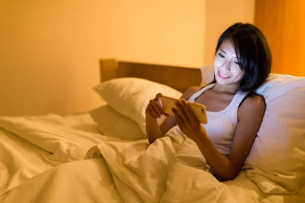 Mulher usando celular na cama à noite — Fotografia de Stock
