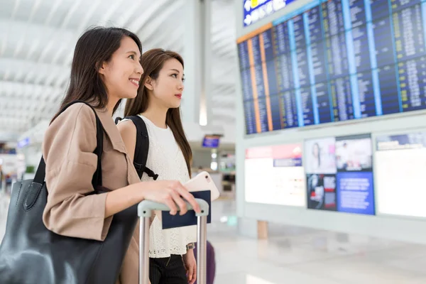 Mulheres verificando o número do voo juntas no aeroporto — Fotografia de Stock