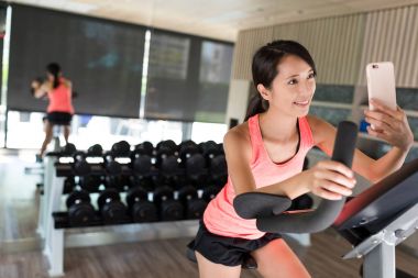 Bisiklete binme ve selfie alarak spor salonunda kadın 