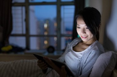 Geceleri dijital tablet üzerinde çalışan kadın