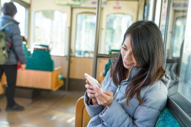 Tren bölmesi üzerinde cep telefonu kullanan kadın