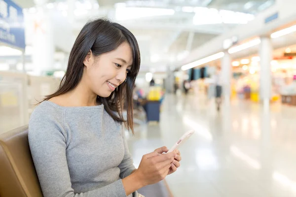 Vrouw met behulp van mobiele telefoon in luchthaven — Stockfoto