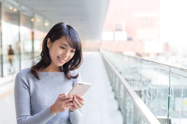 Vrouw met behulp van mobiele telefoon in de stationshal — Stockfoto