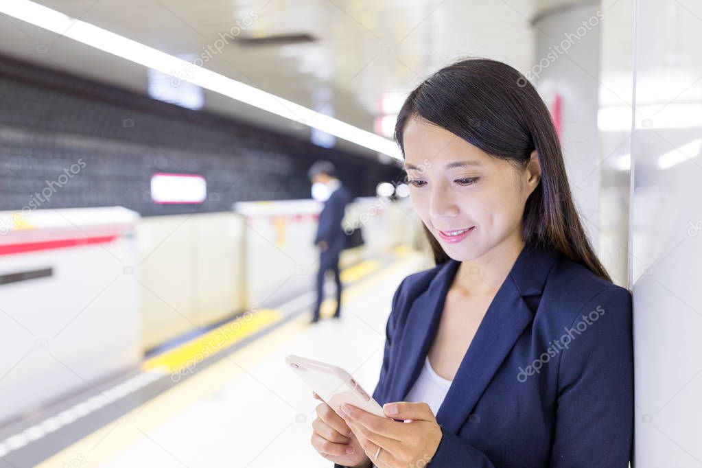 Businesswoman working on cellphone in train platform