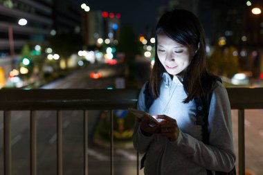 Geceleri cep telefonu kullanan bir kadın.