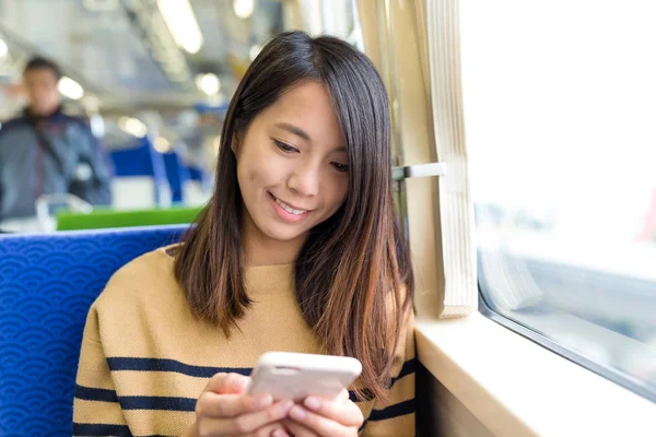 Жінка дивиться на мобільний телефон у потязі — стокове фото