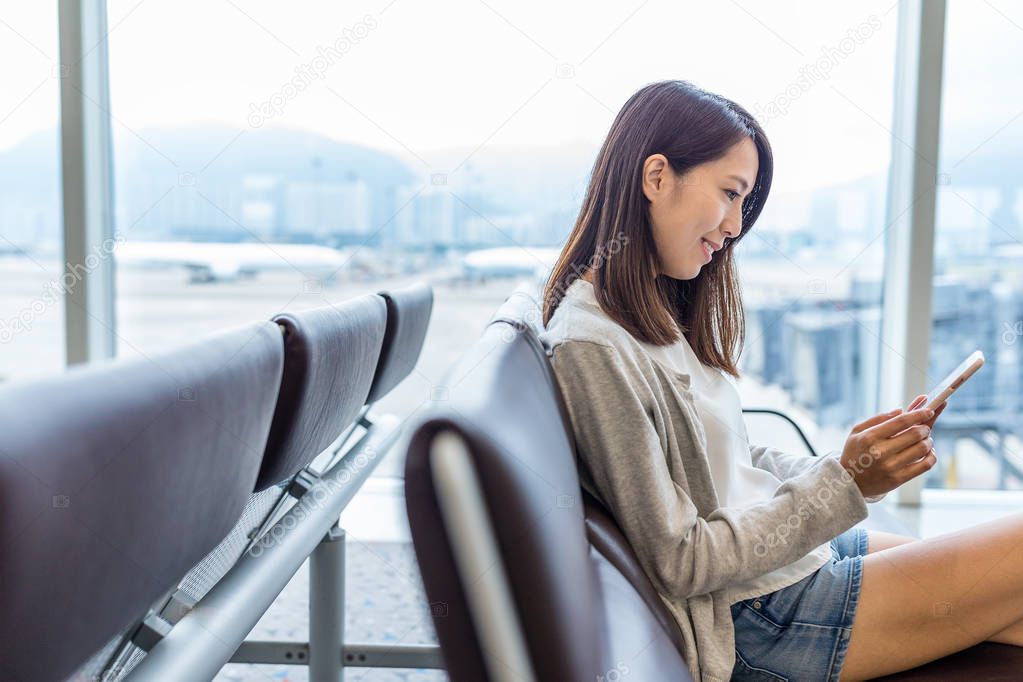 Woman working on mobile phone in airport