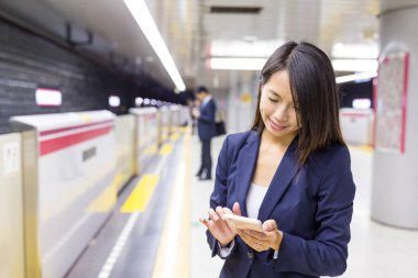 Tren istasyonunda cep telefonu kullanarak iş kadını