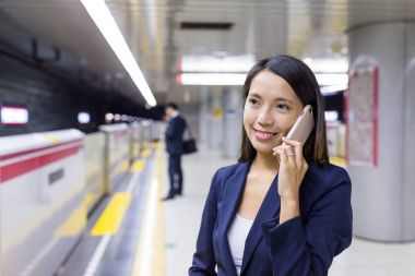 Tren istasyonunda cep telefonu konuşurken işkadını