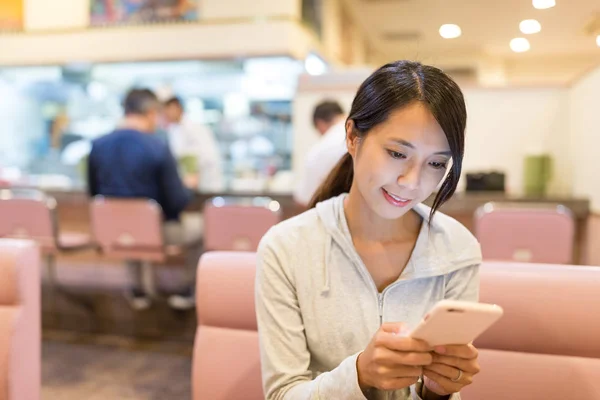 Mulher usando smartphone em um restaurante — Fotografia de Stock