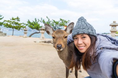 Selfie Itsukushima geyik ile çekici kadın