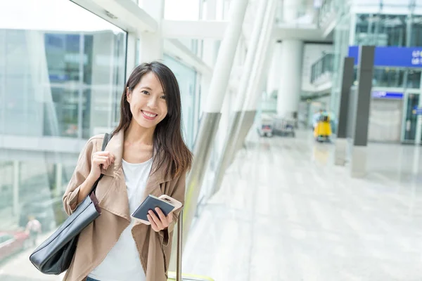 Woman holding cellphone in airport — Stock Photo, Image